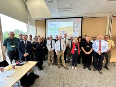 A group of people pose in front of a conference screen