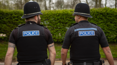 Uniformed police officers walking on patrol, seen from behind