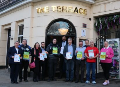 Community safety partners hold up Best Bar None signs outside The Terrace restaurant.