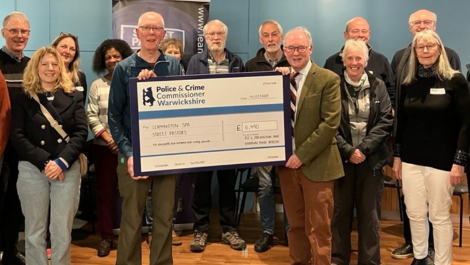 A group of people stand around a giant cheque